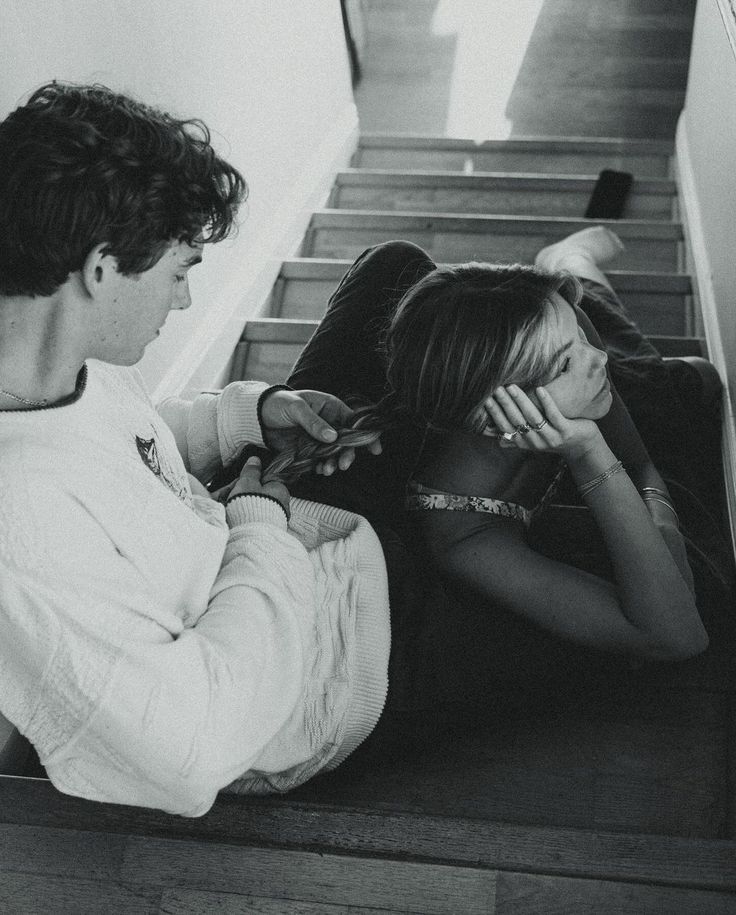 two people are sitting on the stairs and one person is brushing her hair while the other looks down