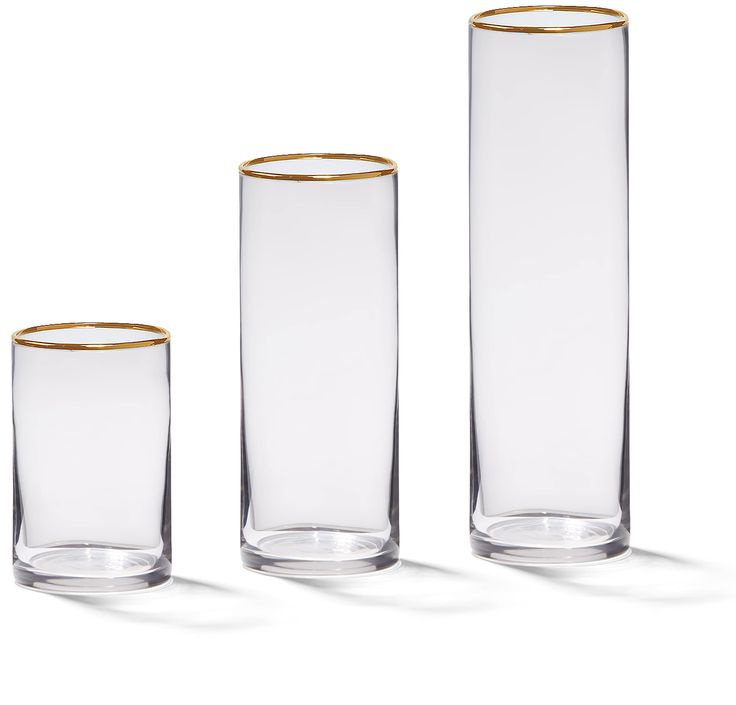 three tall glass vases with gold rims on each one side and the other half empty