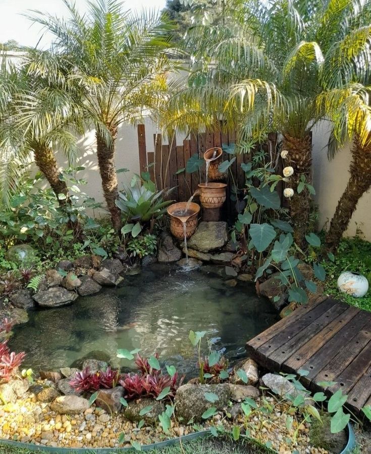 a small pond in the middle of a garden with plants around it and a wooden bench next to it