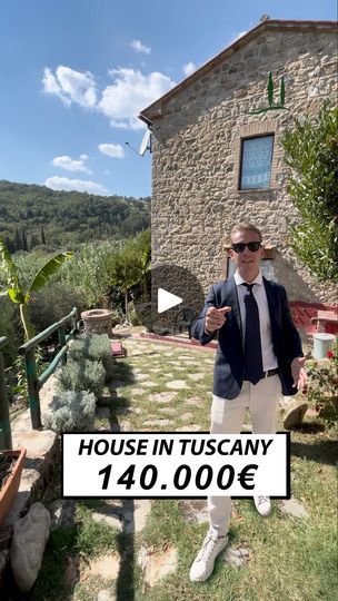 a man standing in front of a house with a sign that says house in tuscany