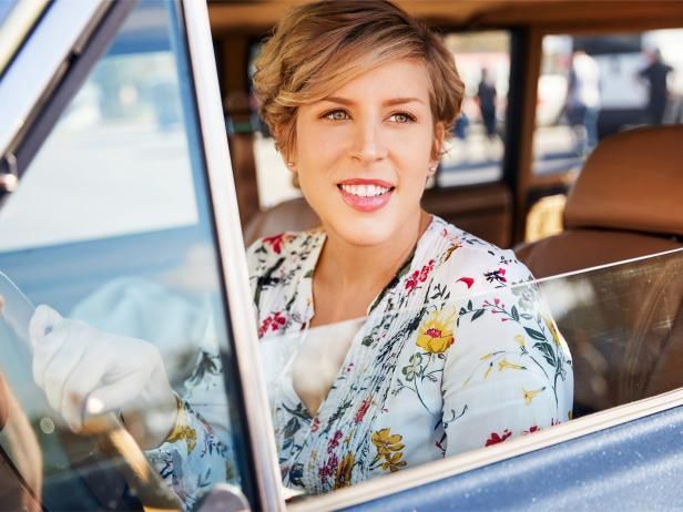 a woman sitting in the driver's seat of a car smiling at the camera