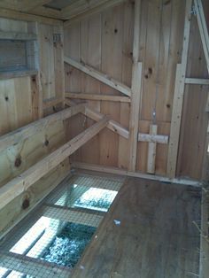 the inside of a chicken coop with wooden walls and flooring, including two windows