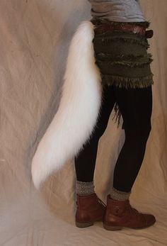 a woman is dressed up in costume and holding a large white fox tail while posing for the camera