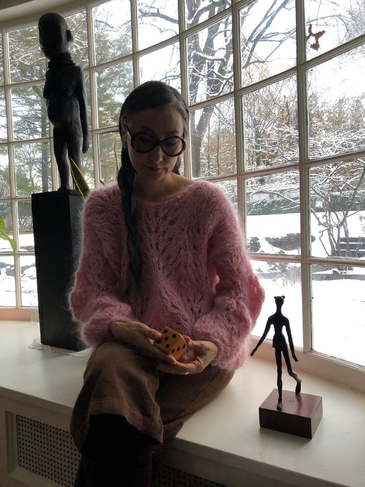 a woman sitting on a window sill holding a cookie