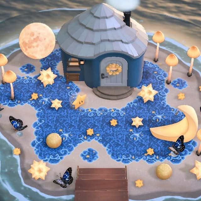 a small blue house surrounded by stars and moon decorations on an island in the ocean