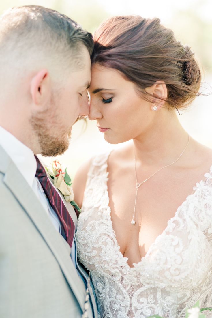 a bride and groom standing close to each other in front of the camera with their eyes closed