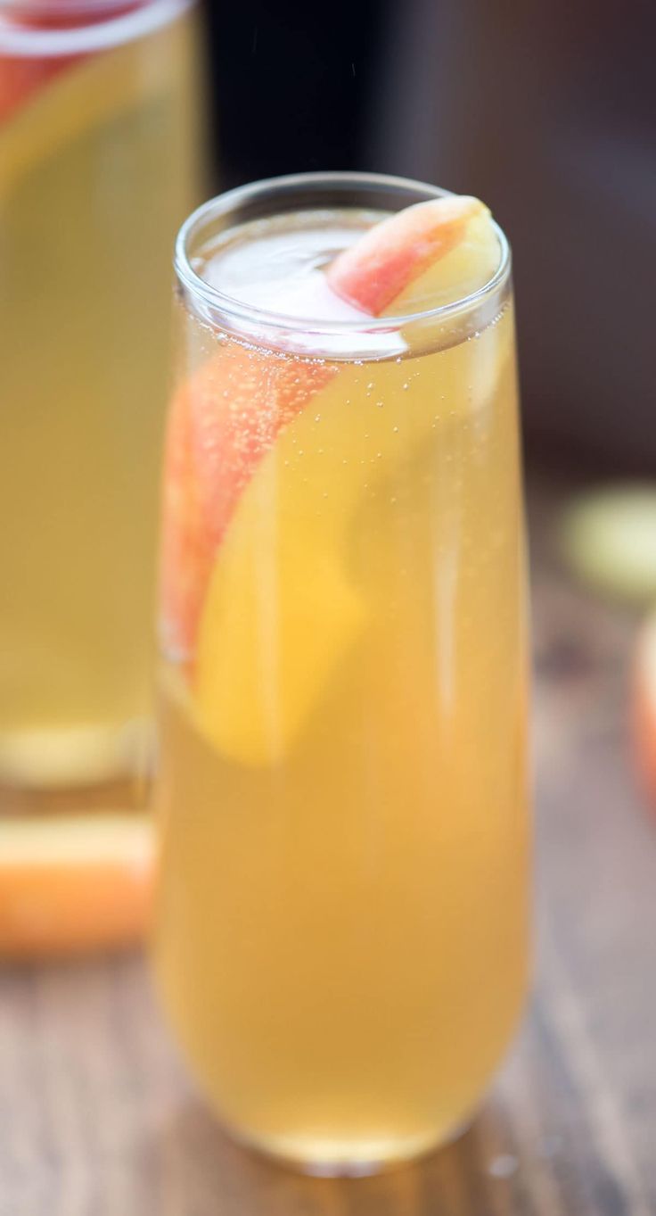 two glasses filled with drinks sitting on top of a wooden table next to each other