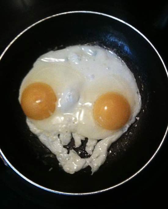 two eggs in a frying pan on top of a stove with the same face