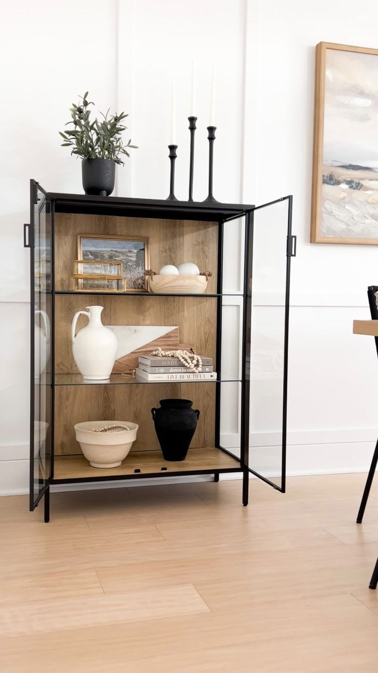 a glass shelf with vases and other items on it in a living room area