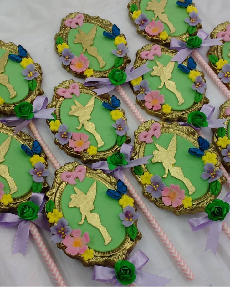 some decorated cookies are on a table with pink and green ribbons around them, as well as flowers