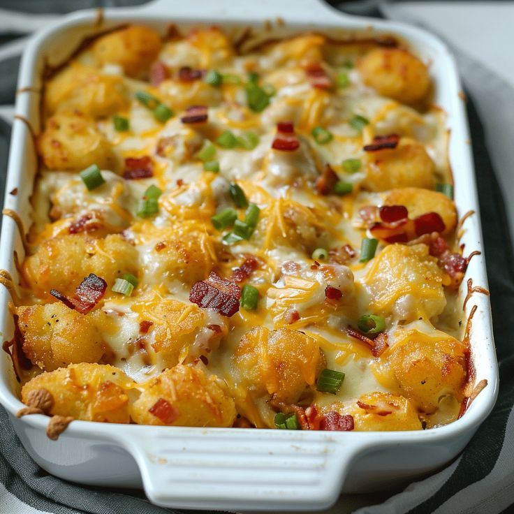 a white casserole dish filled with tater tots covered in cheese and bacon