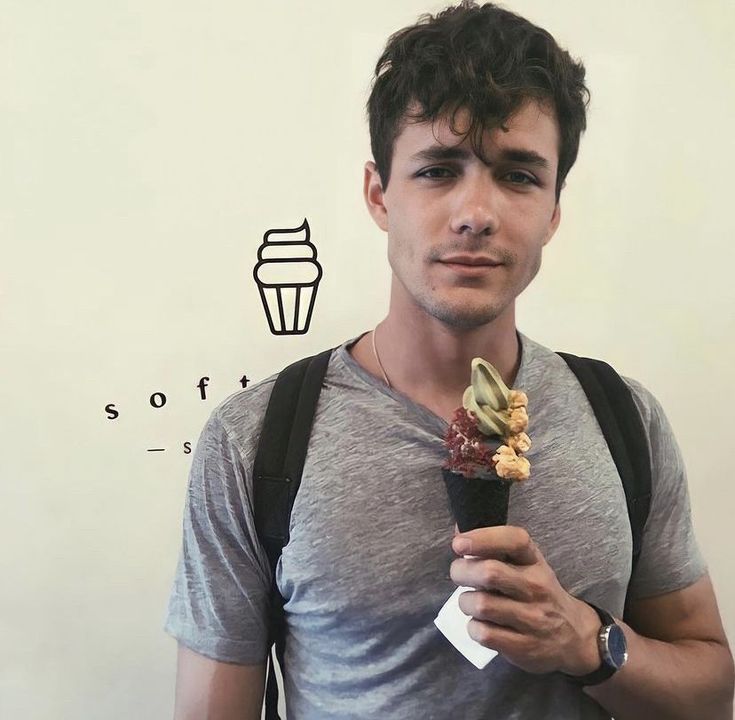 a young man holding an ice cream cone in his hand