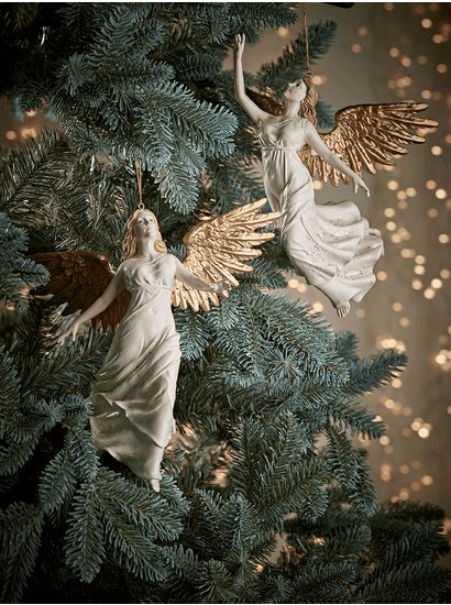 two angel ornaments hanging from a christmas tree