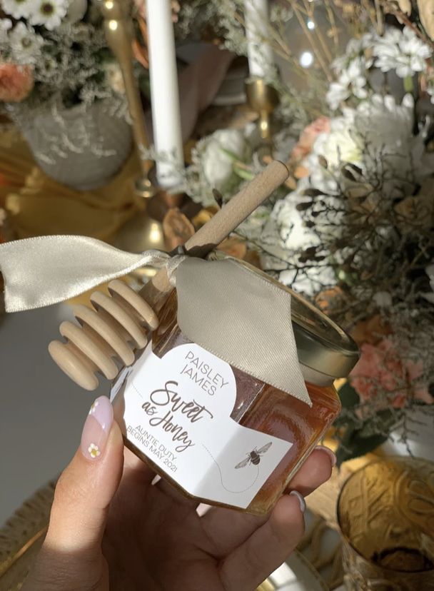 a person holding a jar of honey with a ribbon around it