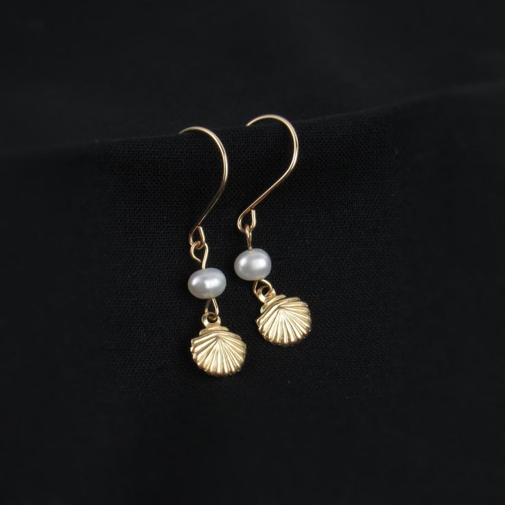 Who doesn't love pearls and seashells? These earrings combine the best of both worlds. You'll love the tiny shell charm and delicate freshwater pearl. A perfect gift for ocean lovers!   ABOUT: * Materials: 14k gold filled wire * Beads: real freshwater pearls and gold filled charm (one-sided, 7mm) * Earring wires: 22 gauge (.64mm) * Lightweight design * Sizing Details: (earring box is 2x3 inches for size reference) * Total Length: 1.25 in. (3cm) * Width: .25 in. (.5cm) SHOP OUR BRAND > https://ro Shell-shaped Pearl Earrings For Gift, Shell-shaped Pearl Drop Earrings For Gifts, Elegant Pearl Charm Earrings With Shell, Elegant Shell Dangle Jewelry, Pearl White Shell-shaped Jewelry With Pearl Drop, Elegant Shell Drop Earrings As Gift, Elegant Gold Dangle Shell Earrings, Elegant Shell Drop Earrings For Gift, Elegant Drop Shell Earrings As A Gift