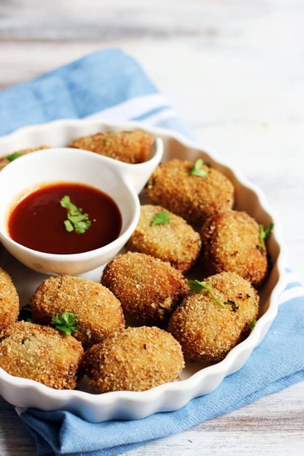 a white bowl filled with fried food next to a dipping sauce on top of a blue towel