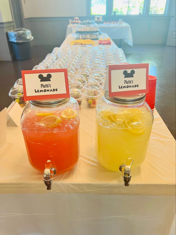 some drinks are sitting on a table with name tags in front of them and mickey mouse