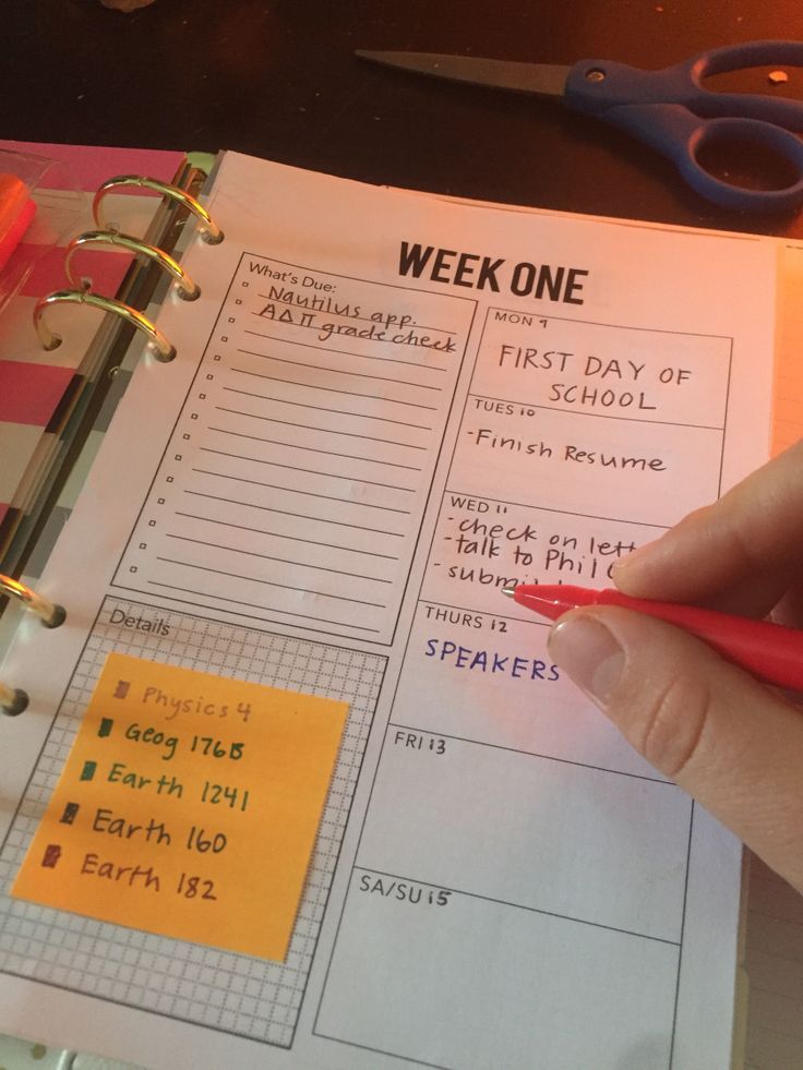 a person holding a pen and writing on a workbook