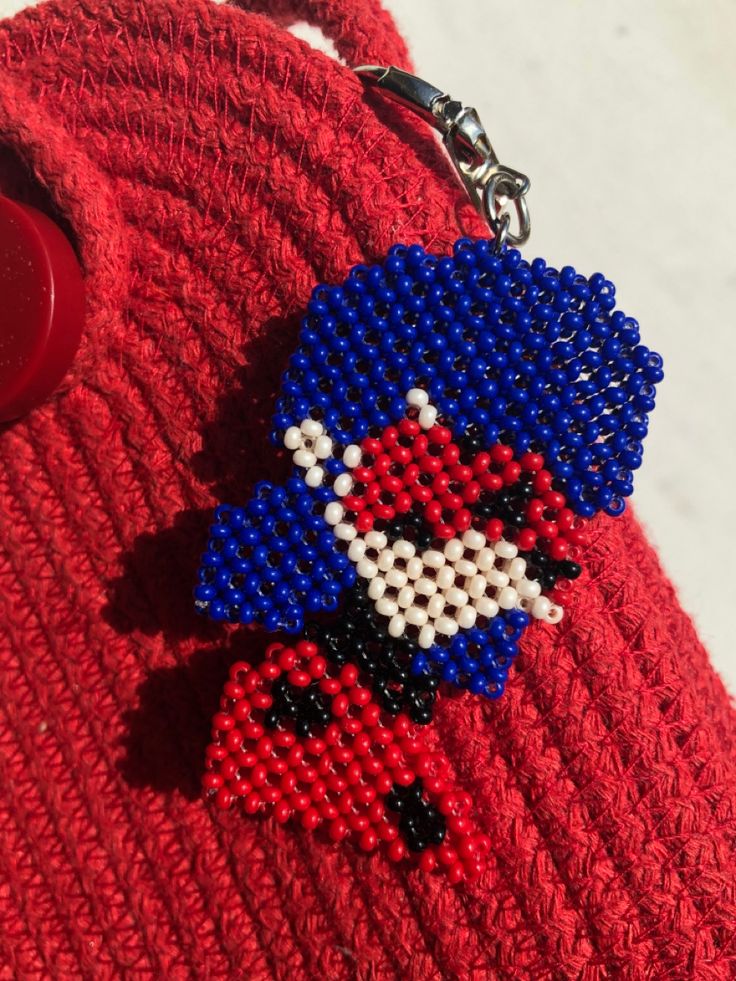 a close up of a person wearing a red sweater holding a blue and white beaded keychain