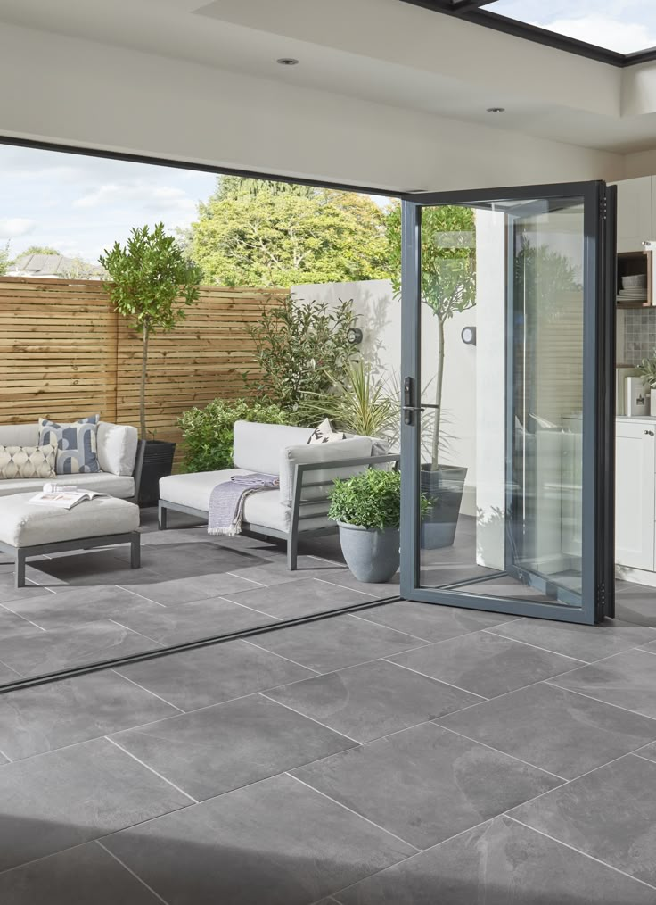 an outdoor patio with grey tiles and white furniture