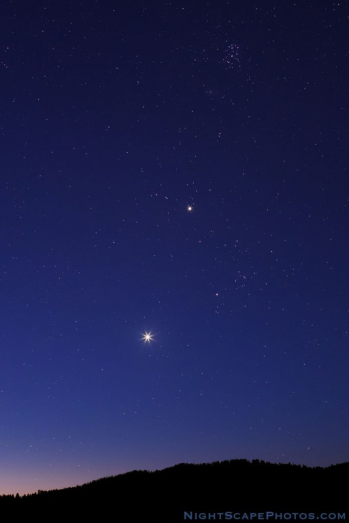 the night sky with two stars in it and one light shining on top of a hill