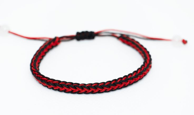 a red and black braided bracelet on a white background