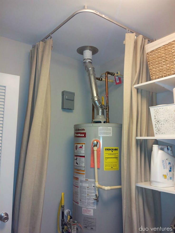 a water heater sitting in the corner of a bathroom next to a shower curtain