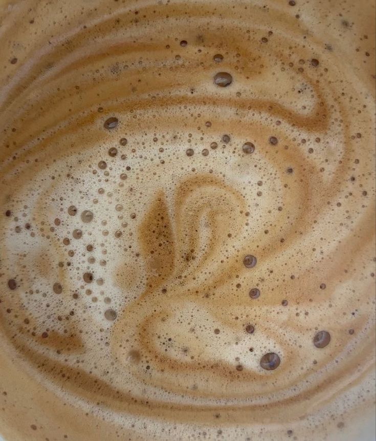 the top view of a coffee cup filled with foamy liquid and brown circles on it