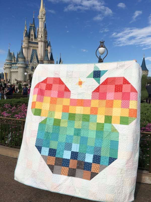 an apple quilt hanging on a fence in front of a castle