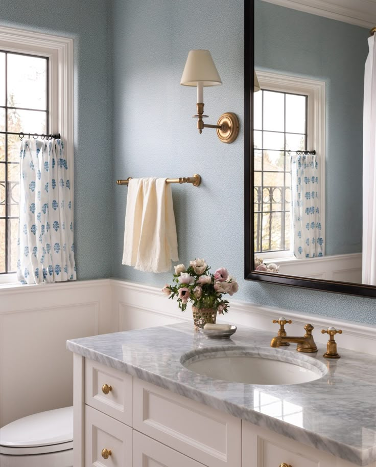 there is a bathroom with blue walls and white counter tops, along with a gold faucet