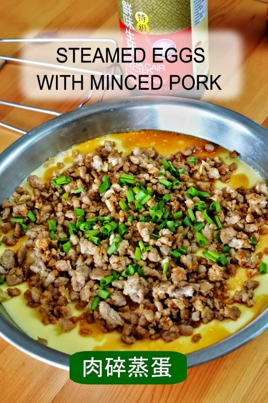 an image of steamed eggs with minced pork in a pan on a wooden table