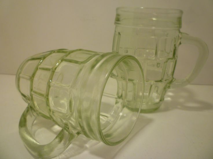 two glass mugs sitting next to each other on a table