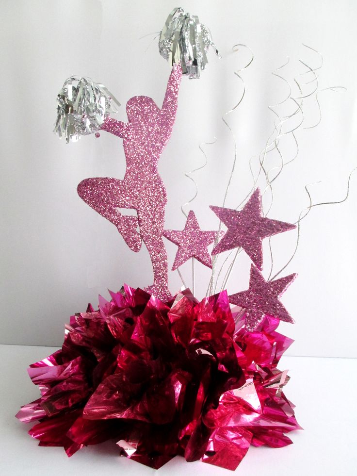 a pink and purple centerpiece with tinsel stars on it's top, in front of a white background