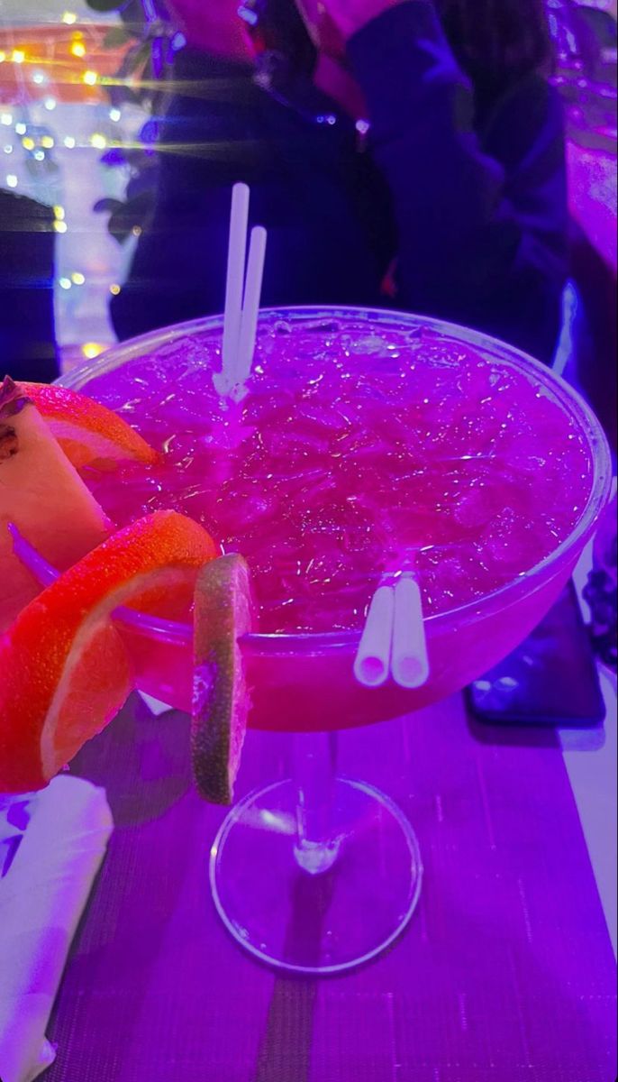 a pink drink with orange slices and garnishes in a large glass bowl