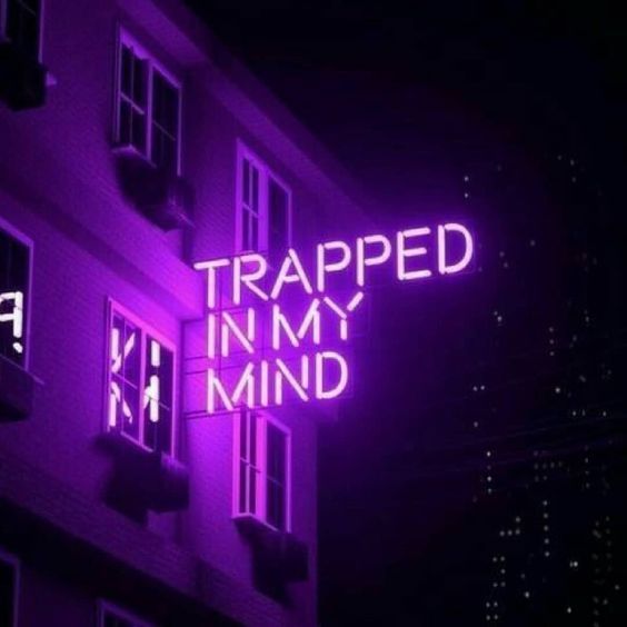 a neon sign that reads trapped in my mind on the side of a purple building