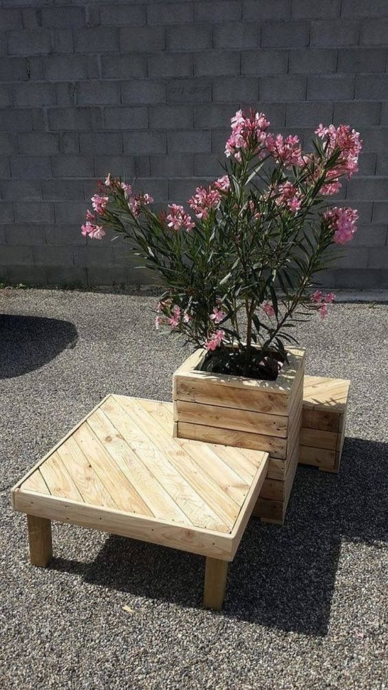 a wooden planter sitting on top of a cement ground next to a flower pot