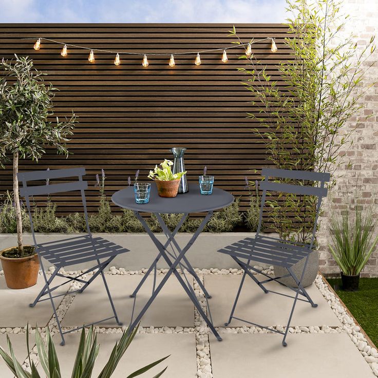 an outdoor table and chairs with potted plants