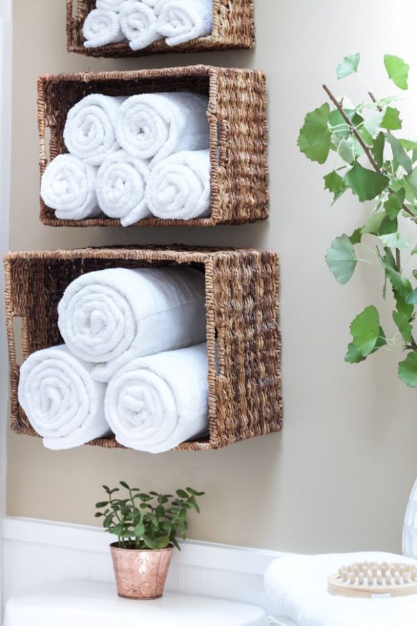 two baskets with towels are hanging on the wall next to a plant in a bathroom