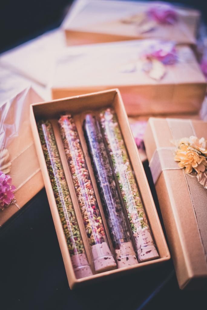 several different colored pencils in a box on a table next to flowers and other items