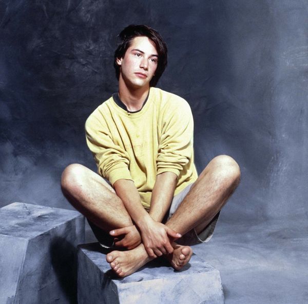 a young man sitting on top of a cement block