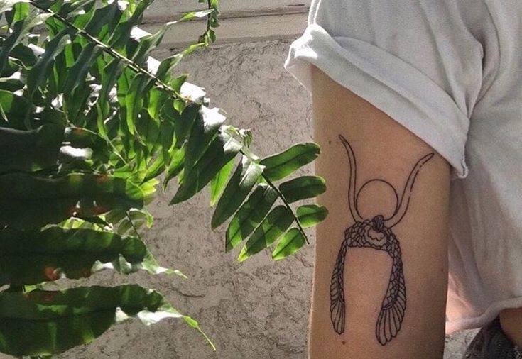 a woman's arm with a tattoo on it and a plant in the background