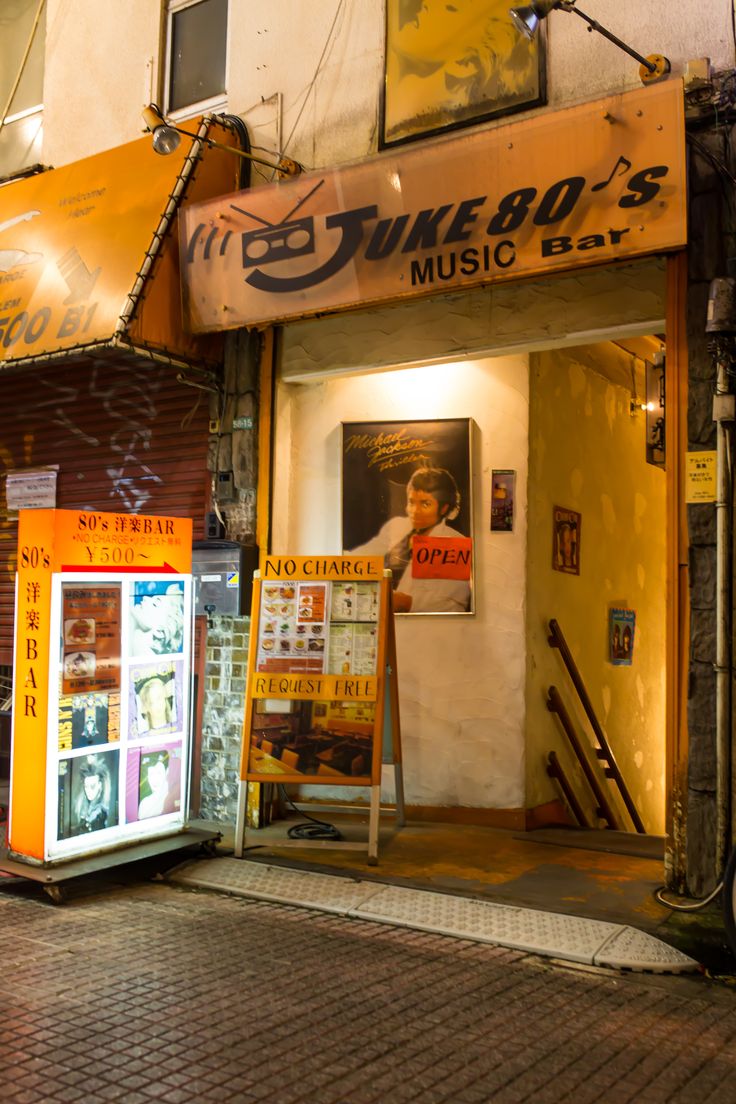 the entrance to a music store with posters on the front and side windows at night