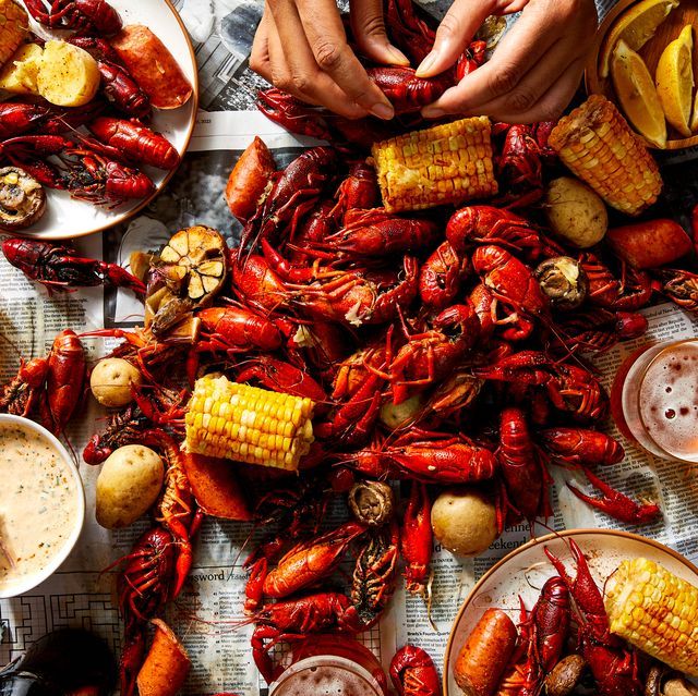 people are eating craws and corn on the cob at a table full of food