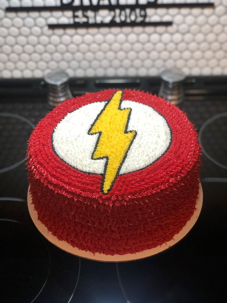 a red and white cake with a yellow lightning on it's side sitting on top of a stove