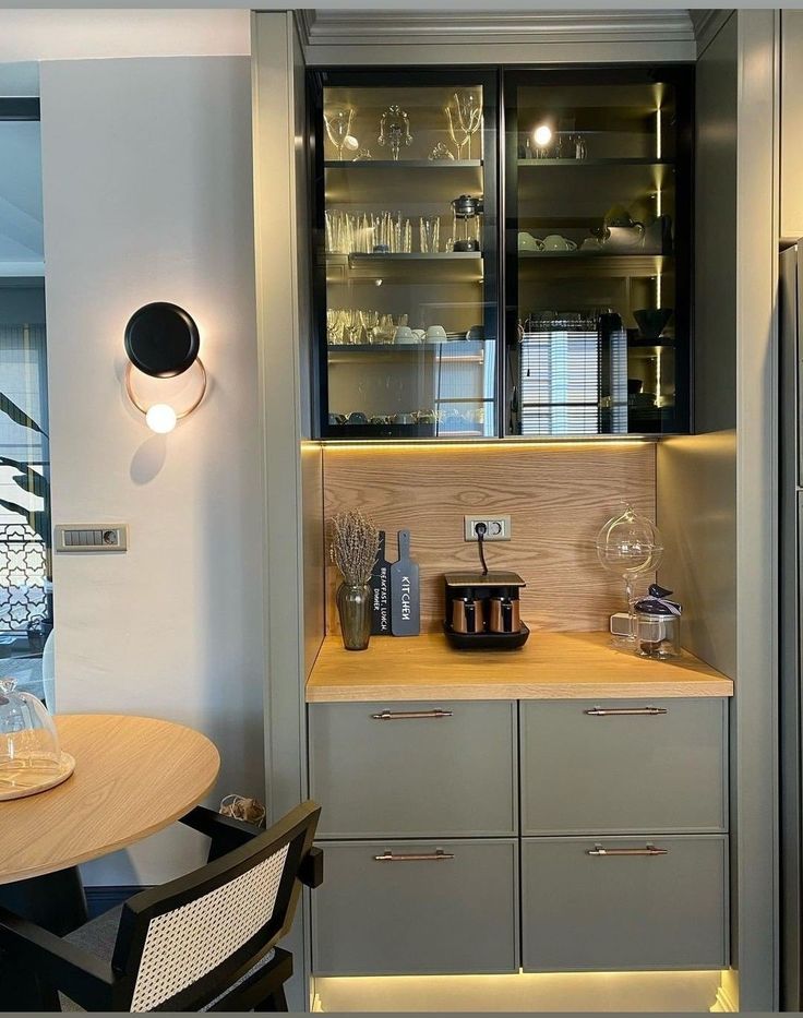 a room with a table, chairs and cupboards in front of the door that has wine glasses on it