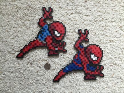 two spider - man pixelated magnets sitting on top of a white carpet next to a coin