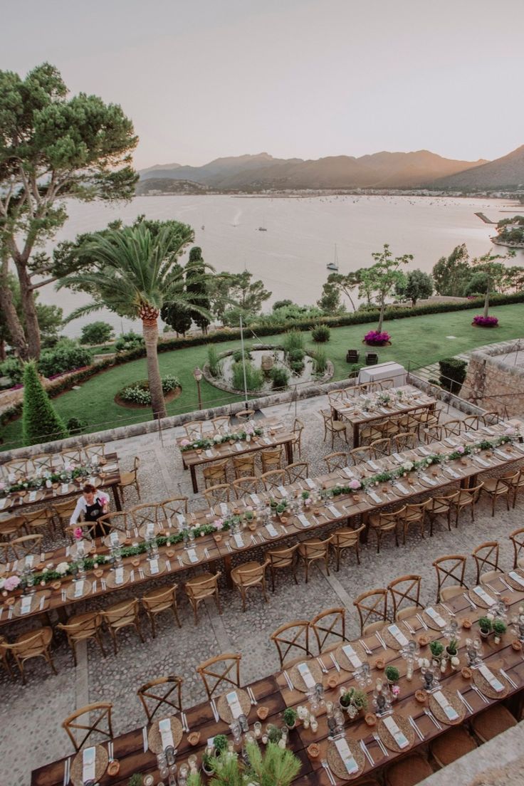 an outdoor dining area with tables and chairs set up for dinner next to the water