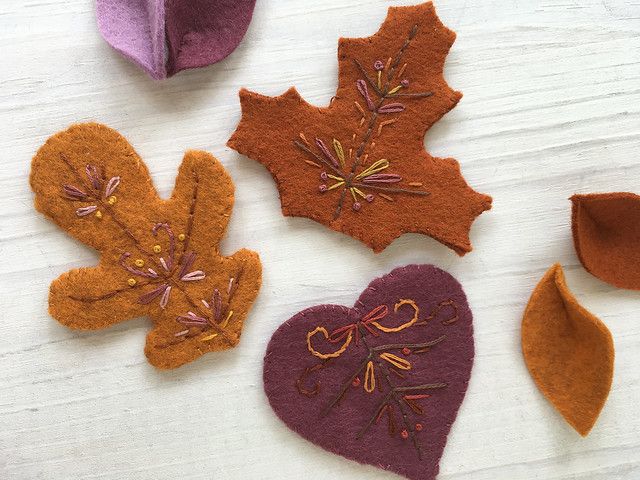 four felt leaves are arranged on a white surface, one is purple and the other is orange