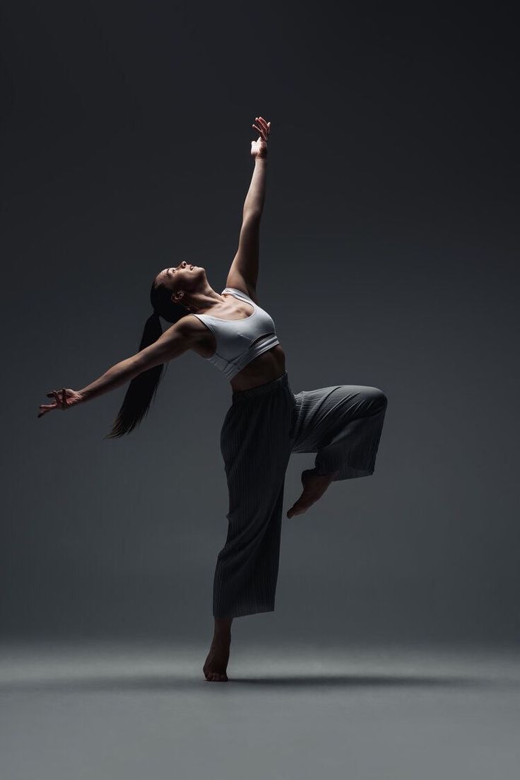 a woman in white shirt and black skirt doing a dance pose with her arms outstretched