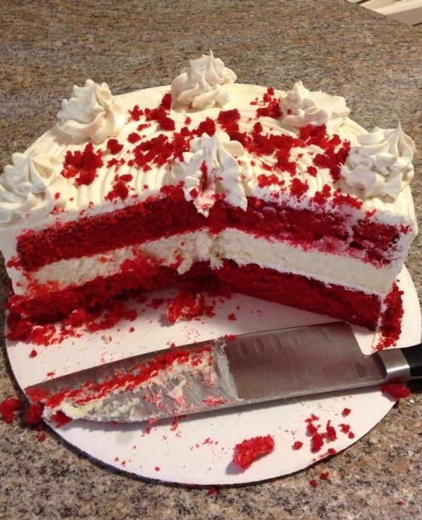 a cake with white frosting and red sprinkles on it next to a knife